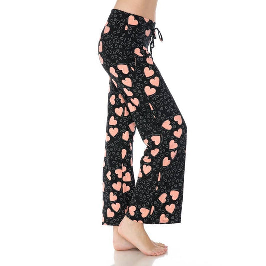 A person stands sideways, shown from mid-torso to feet, wearing Leggings Depot's Buttery Soft Pajama Pants with pink and white hearts and an elastic waistband.
