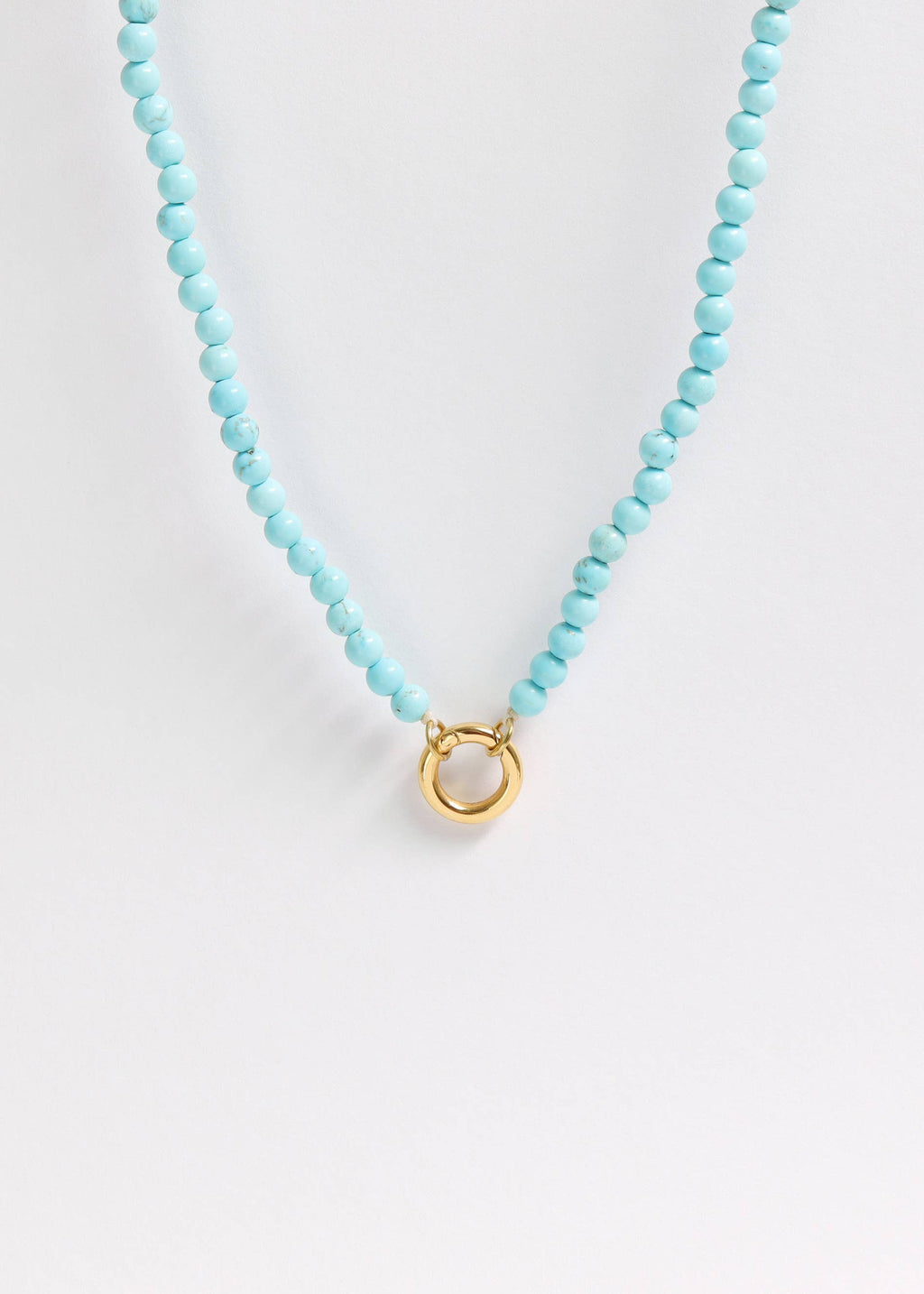 A close-up of the WJW Semi Precious Natural Stone Charm Keeper Necklace, featuring round turquoise beads and a central 18K Gold PVD Coated circular clasp, displayed on a plain white background.