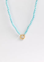 A close-up of the WJW Semi Precious Natural Stone Charm Keeper Necklace, featuring round turquoise beads and a central 18K Gold PVD Coated circular clasp, displayed on a plain white background.