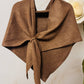 The JC Sunny Fashion Cashmere-Blend Knit Triangle Shawl with Cross-Front Design, in brown, is tied loosely and displayed against a light background with a white artificial rose partially visible on the right.