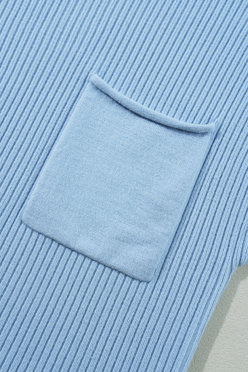 Close-up of Shewin's Patch Pocket Ribbed Knit Short Sleeve Sweater in light blue, featuring a square pocket that adds charm or creates a cozy ambiance.