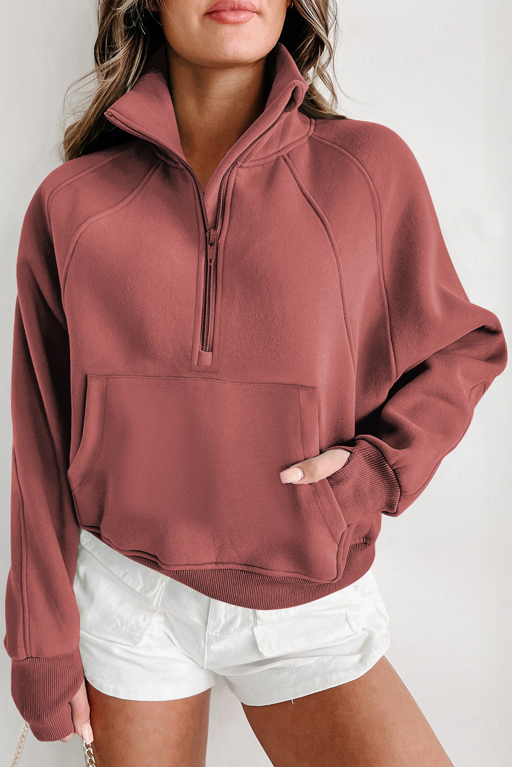 A person with long hair wears the Shewin Gray Zip Up Stand Collar Ribbed Thumbhole Sleeve Sweatshirt and white shorts against a plain background.