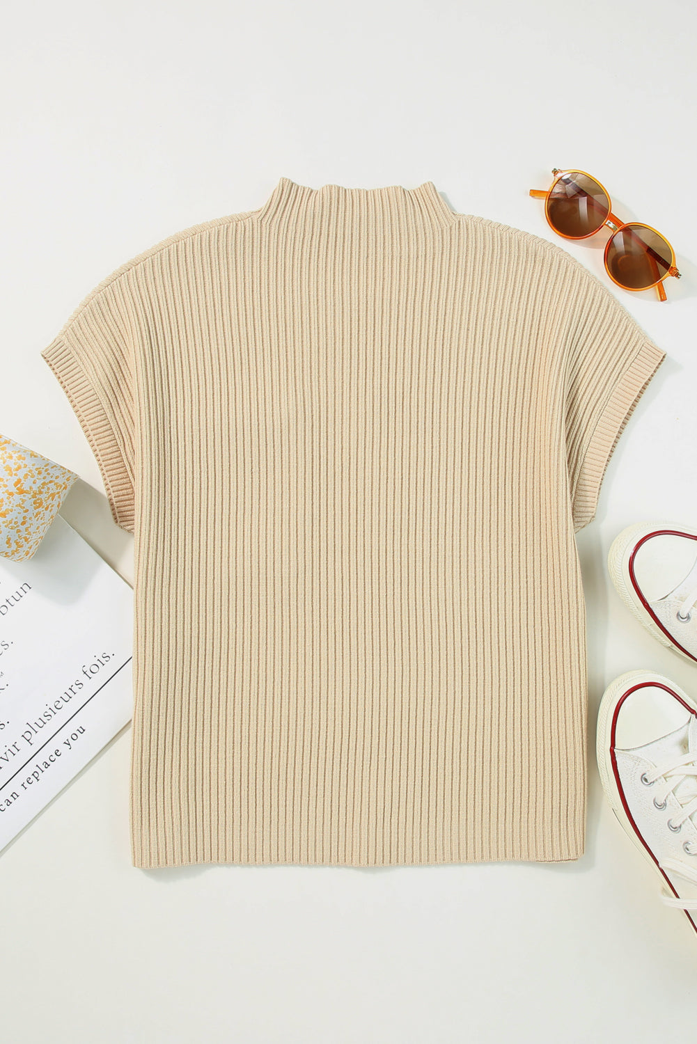 A flat-laid Patch Pocket Ribbed Knit Short Sleeve Sweater by Shewin in beige appears ideal for transitional weather, surrounded by sunglasses, an open book, and white sneakers with red accents.