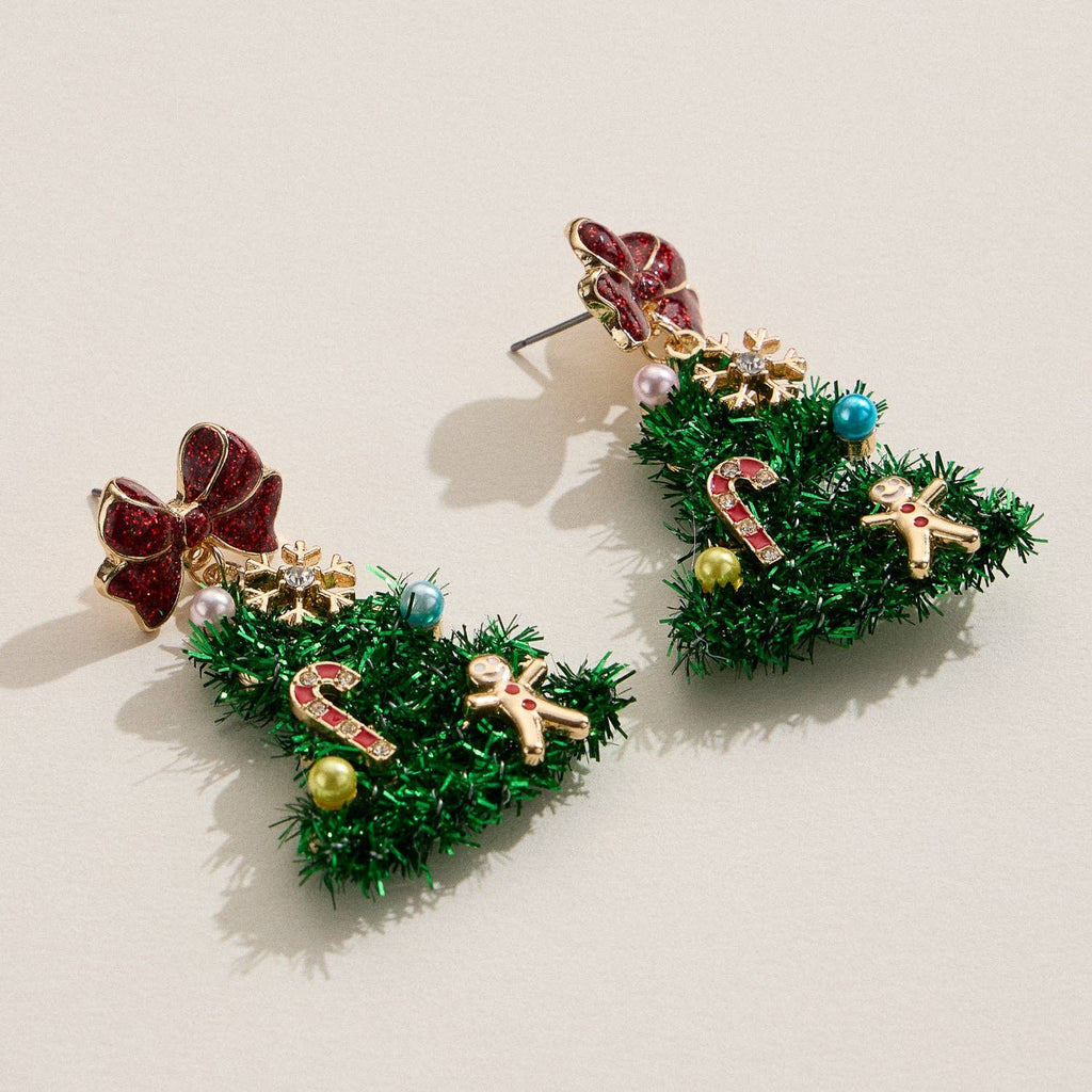 Bring festive flair to your style with the Tinsel Christmas Tree Drop Earrings by Lilla Haven—a delightful pair of holiday statement earrings adorned with colorful ornaments, finished with a red bow on top, and featuring playful candy cane and gingerbread man charms. These Holiday Ornament Charm earrings are perfect for spreading holiday cheer!.