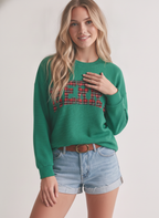 A person wearing a green Merry Plaid Cloudy Knit Top with light-wash denim shorts and a brown belt.
