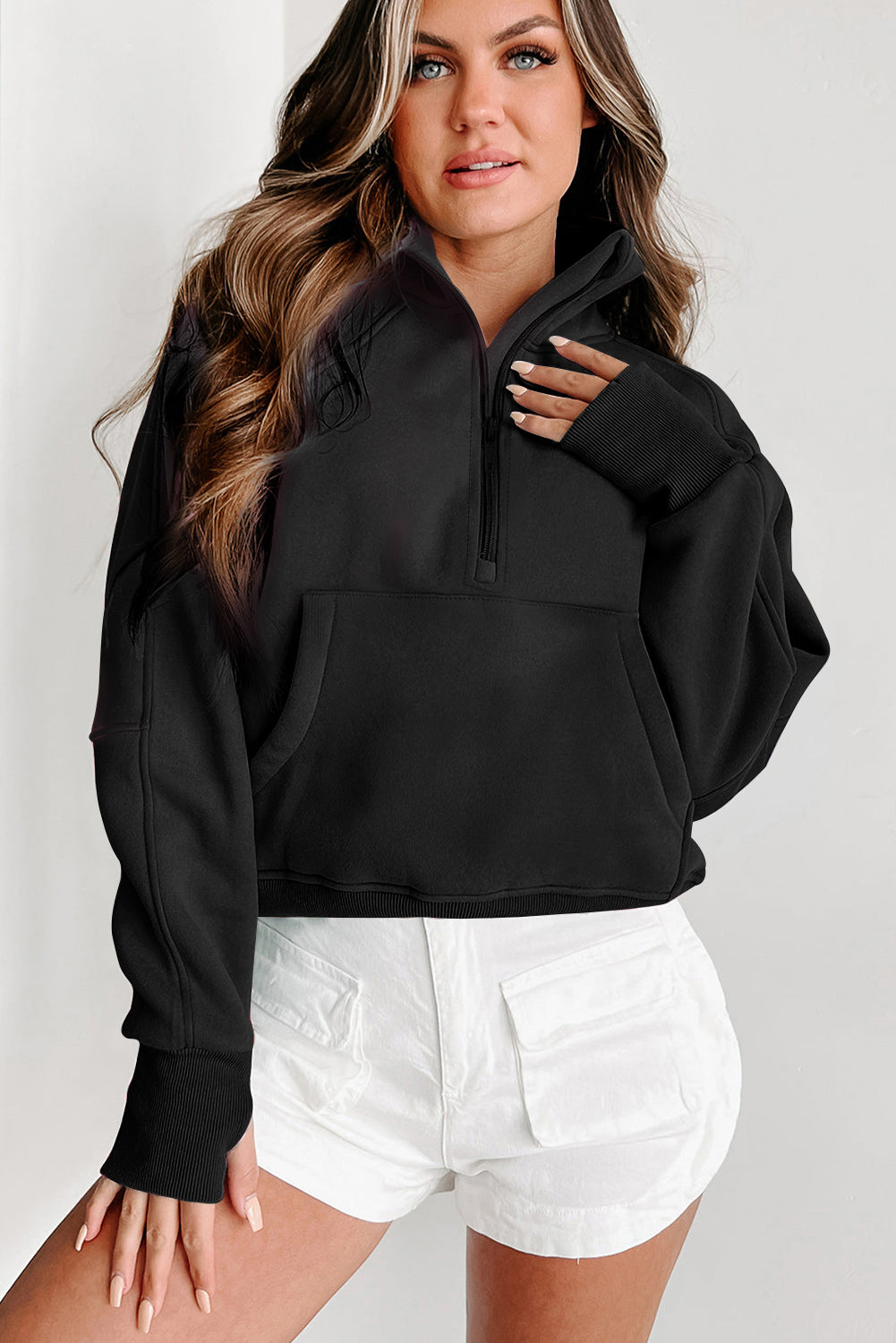 A woman with long wavy hair wears a Shewin gray zip-up stand collar ribbed thumbhole sleeve sweatshirt made of high-quality material and white shorts.