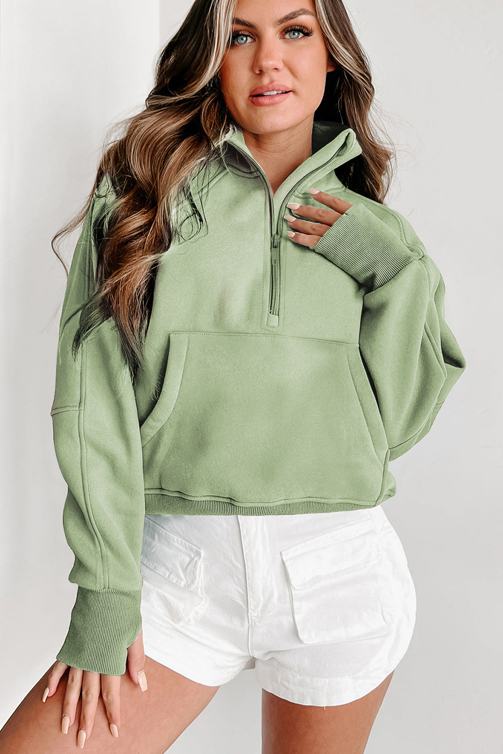 A woman with long wavy hair wears a Shewin gray zip-up stand collar ribbed thumbhole sleeve sweatshirt made of high-quality material and white shorts.