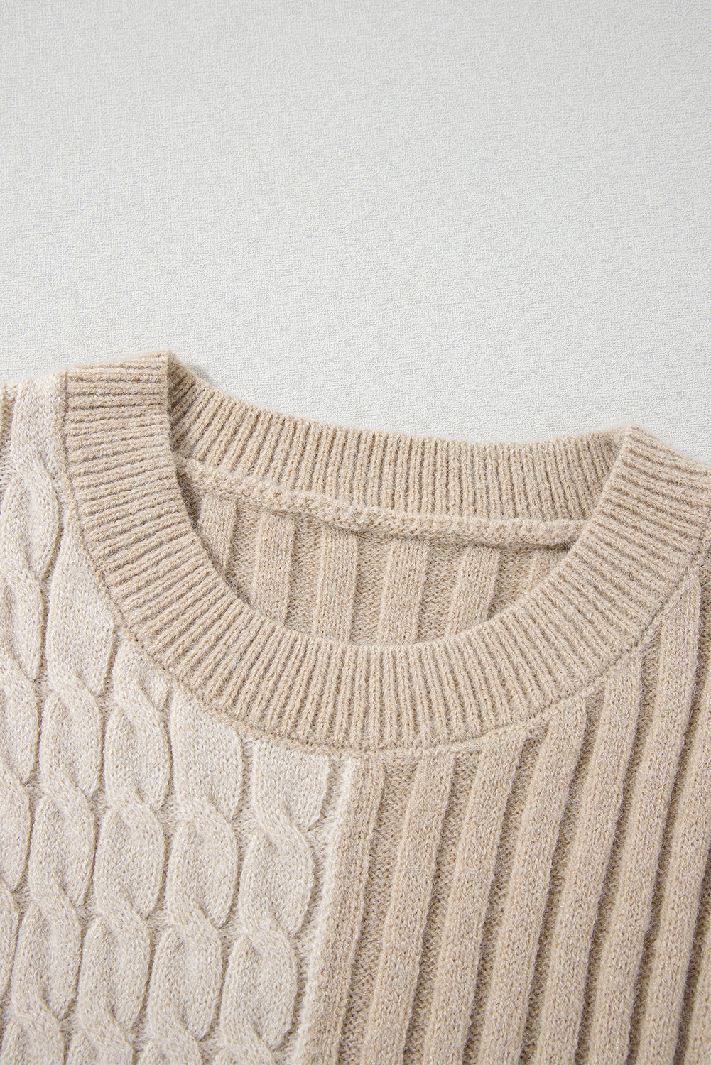 A close-up of the Shewin Khaki Cable Knit Colorblock Crew Neck Drop Shoulder Sweater highlights its mix of cable and ribbed patterns, enriched with detailed rib-knit elements.