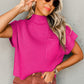 Wearing a Shewin Patch Pocket Ribbed Knit Short Sleeve Sweater in pink and sunglasses, paired with brown pants, this person stands against a gray wall with one hand touching their ear, showcasing ideal transitional weather style.