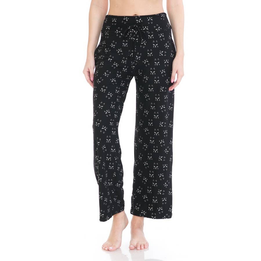 A person stands barefoot against a plain white background wearing Leggings Depot Buttery Soft Print Pajama Pants featuring a white bow pattern and an elastic waistband.