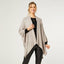 A woman smiles, wearing the COCO + CARMEN Kiara Light Weight Wrap over a black top and black leather-look pants against a plain white background.