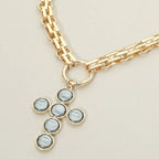 Discover the Pearl Cross Charm Pendant Chunky Chain Statement Necklace by Sensibling Corp.—an elegant gold chain necklace featuring a textured cross pendant, beautifully crafted with six round, grayish-white pearl-like stones set in gold, and finished with a circular clasp for a timeless touch.