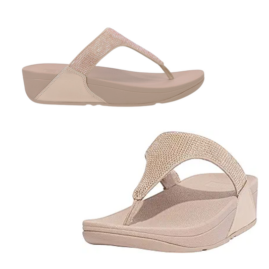 A pair of Lulu Crystal Embellished Flip Flop in Latte Beige by FIT FLOP USA LLC with textured straps adorned with shimmering crystals. The soles are thick with a slight incline.