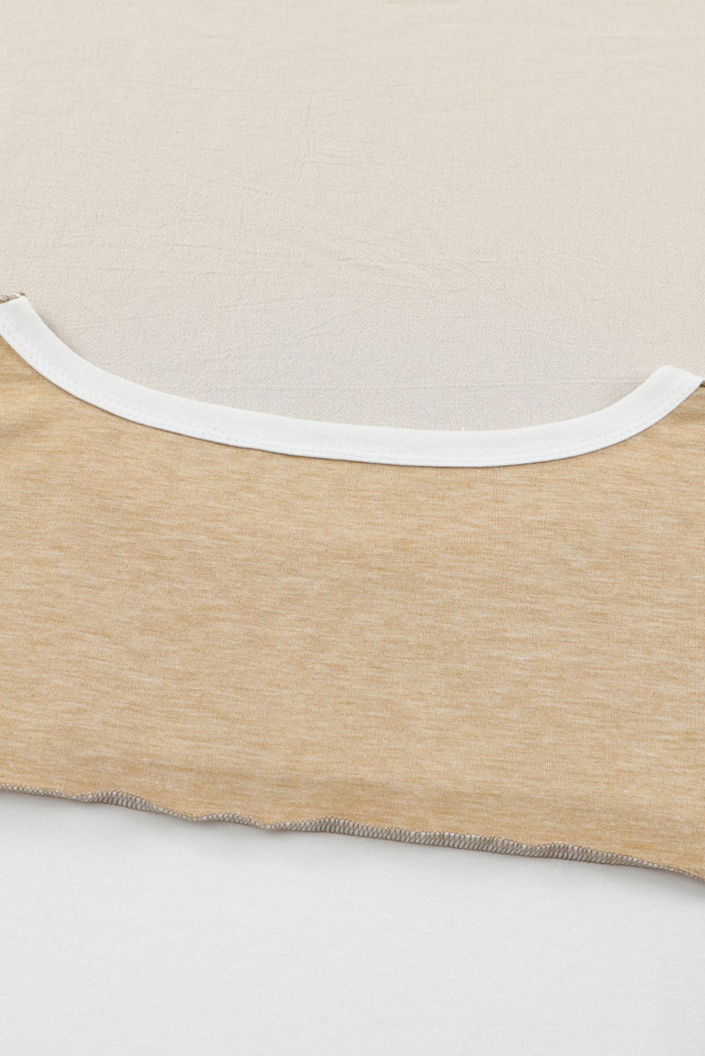 Close-up view of the Shewin Khaki Color Block Exposed Seam Long Sleeve Top, featuring intricate neckline and stitching details, with a distinctive patchwork design.