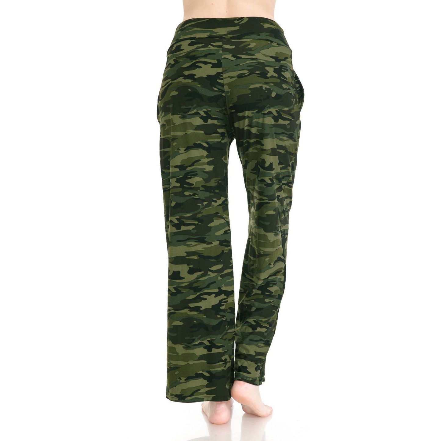 A person stands barefoot, facing away, wearing Leggings Depot Buttery Soft Print Pajama Pants in a green camouflage pattern. The image highlights the lower body and legs against a white background.