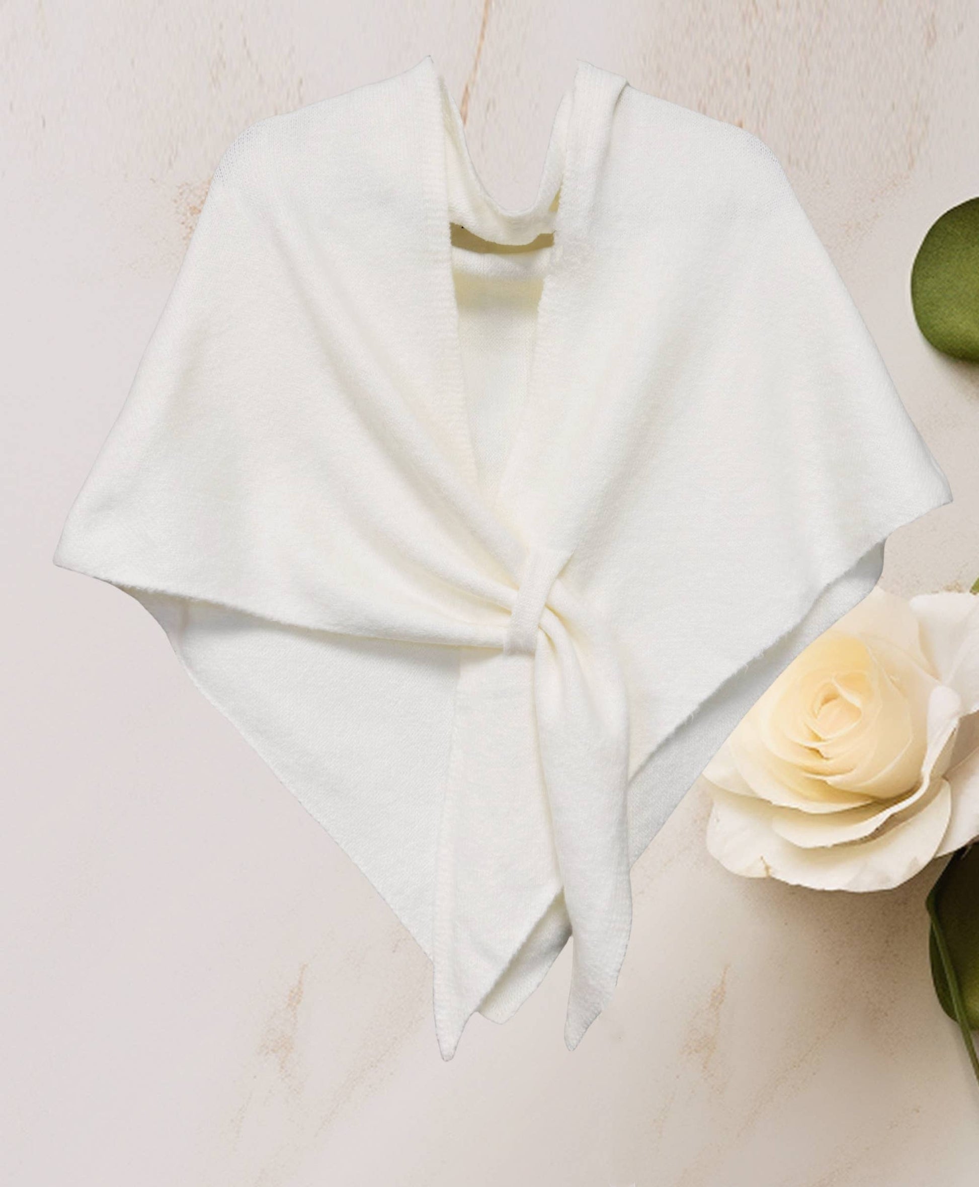 The JC Sunny Fashion Cashmere-Blend Knit Triangle Shawl features a cross-front design, elegantly tied at the center and styled on a light surface beside a white rose and green leaves for a chic look.