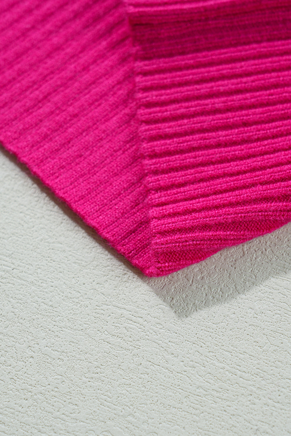 Zoomed-in view of the Shewin Patch Pocket Ribbed Knit Short Sleeve Sweater in pink, resting on a textured light gray surface.