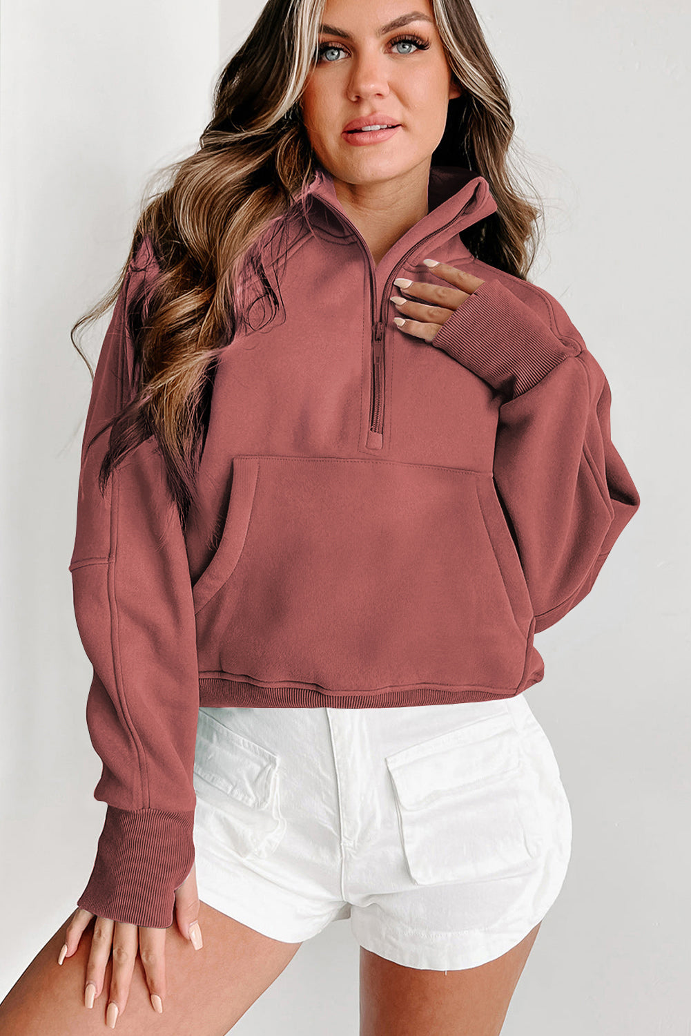 A person with long hair wears the Shewin Gray Zip Up Stand Collar Ribbed Thumbhole Sleeve Sweatshirt and white shorts against a plain background.