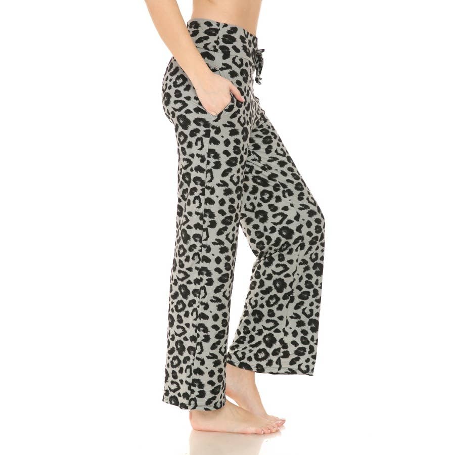 A person models Leggings Depot's Buttery Soft Print PJ Pants in a wide-leg leopard print, hands in pockets and barefoot on a white background.