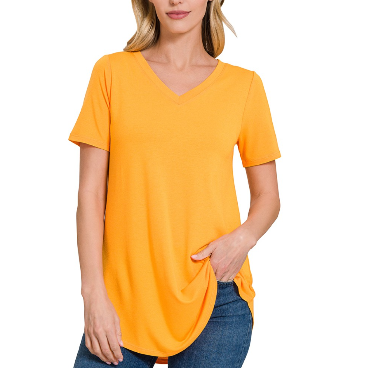 A woman wearing an orange Short Sleeve V-Neck Round Hem T-Shirt from FASHION GO and blue jeans with a relaxed fit, standing with one hand in her pocket.