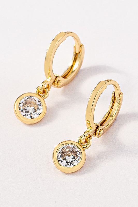 Pair of brass huggie hoops with a dangling round CZ pendant on a white background by FASHION GO.