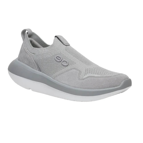 The Oofos Glide Grey Sneaker by oofos features a breathable knit mesh upper in light gray, suede accents, two small round side buttons, and a thick white sole. Main image