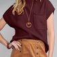 A woman embodies effortless style in a burgundy Shewin Patch Pocket Ribbed Knit Short Sleeve Sweater, elegantly paired with a brown buttoned skirt. Her look is completed with a circular pendant necklace and bracelet, perfect for transitional weather days.