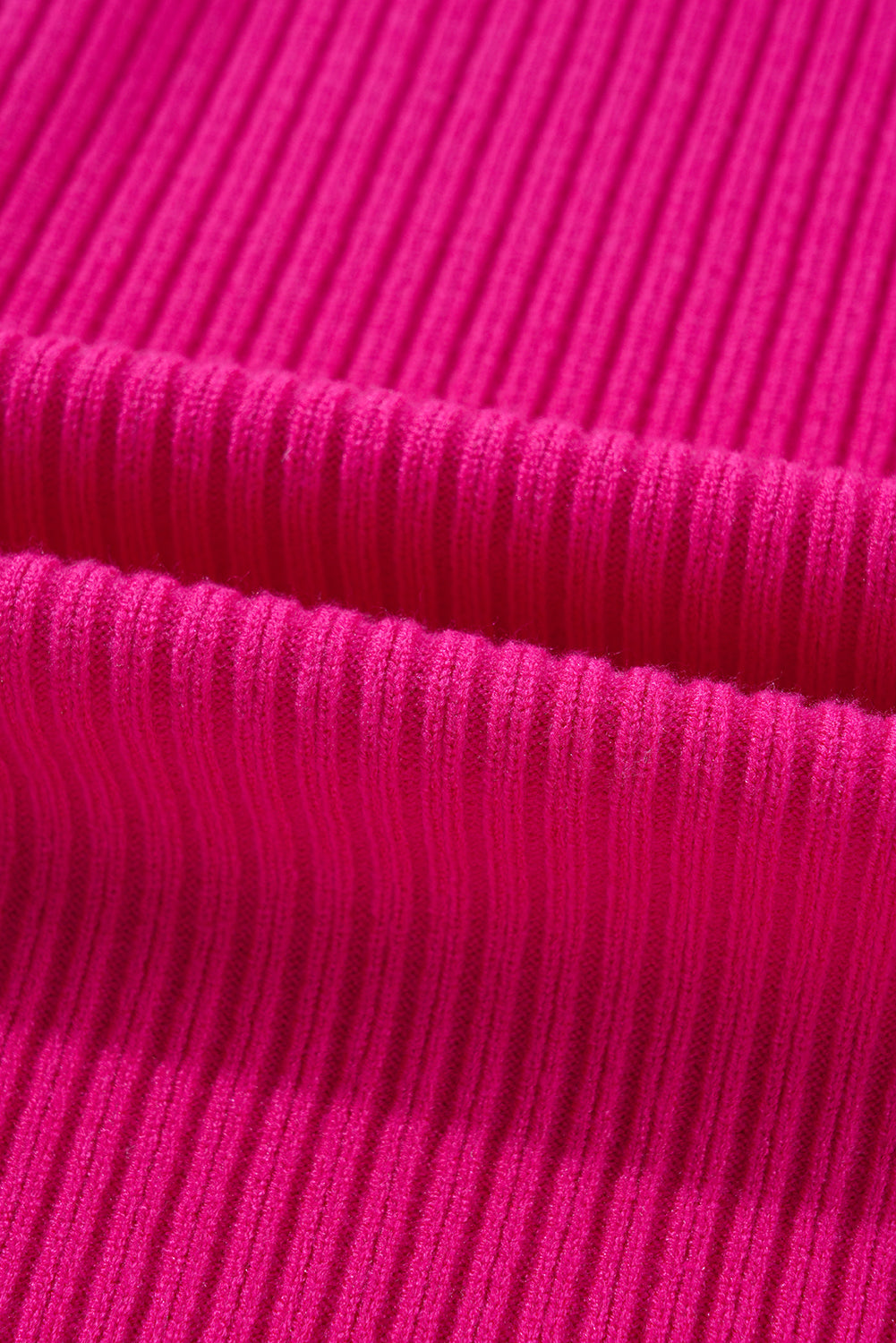 A close-up of the Patch Pocket Ribbed Knit Short Sleeve Sweater by Shewin shows its pink ribbed knit fabric with a wavy texture, evoking a cozy sweater feel.