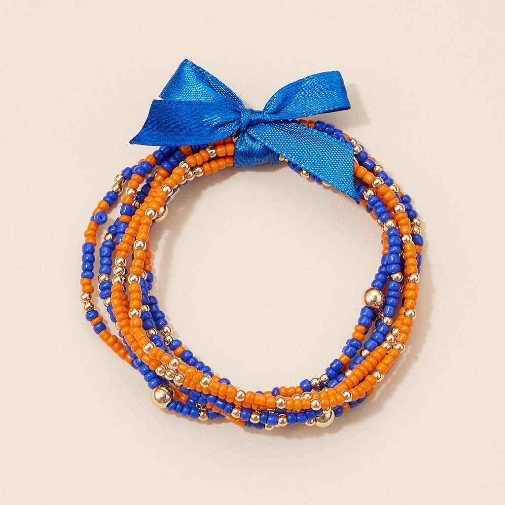 A stack of Game Day Seed Beaded Bracelet Set bracelets in orange and blue, tied together with a blue ribbon.