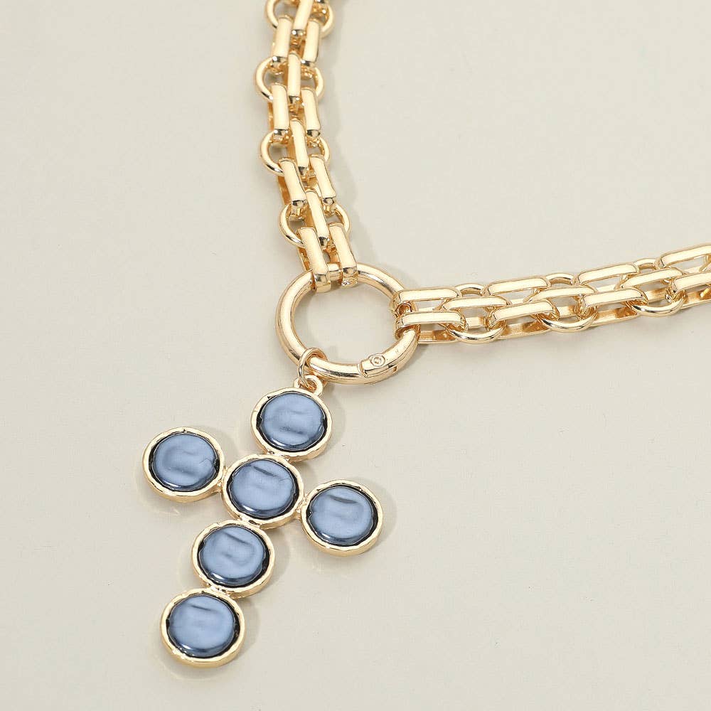 Sensibling Corp.’s Pearl Cross Charm Pendant Chunky Chain Statement Necklace, featuring a textured cross pendant with a striking blue stone, is displayed against a neutral background.