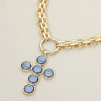 Sensibling Corp.’s Pearl Cross Charm Pendant Chunky Chain Statement Necklace, featuring a textured cross pendant with a striking blue stone, is displayed against a neutral background.