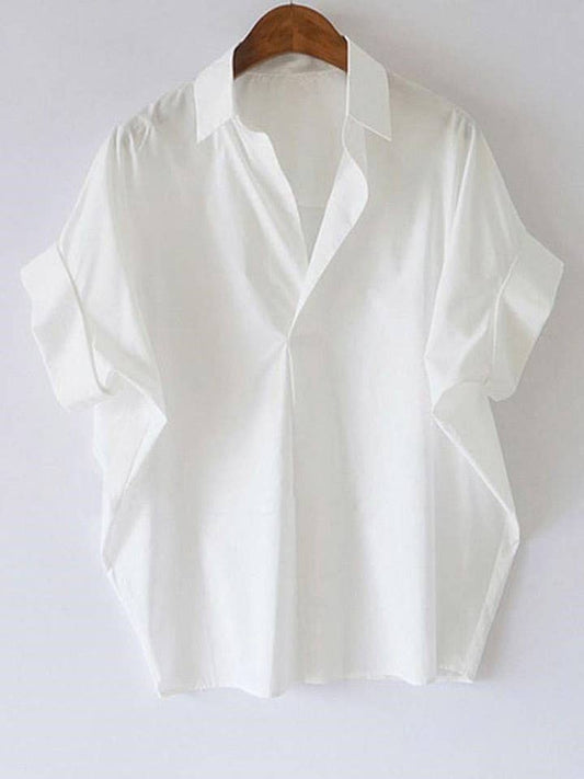 The Rosa Clothing White Relaxed Short Sleeve Blouse hangs on a wooden hanger against a white background, adding a chic touch to any outfit.