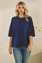 A person wears a navy blue CLOUDY KNIT 3/4 SLEEVE ROUND NECK TOP paired with blue jeans.