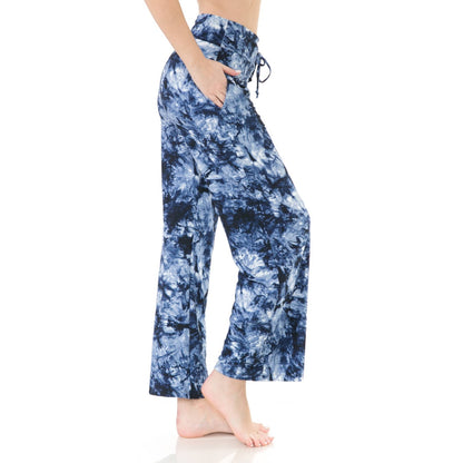 A person stands barefoot with hands in pockets, wearing Leggings Depot Buttery Soft Print Pajama Pants in blue and white tie dye, featuring an elastic waistband, photographed against a white background.