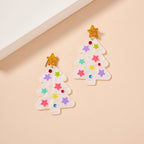 Add a festive touch to your holiday look with the Glittery Christmas Tree Drop Earrings by Lilla Haven. These holiday acrylic earrings feature two white Christmas tree shapes adorned with colorful star decorations and sparkling gold star tops, all shining beautifully on a beige background. Perfect as statement jewelry, these earrings are designed to make your celebrations bright and joyful while ensuring you stand out in style.