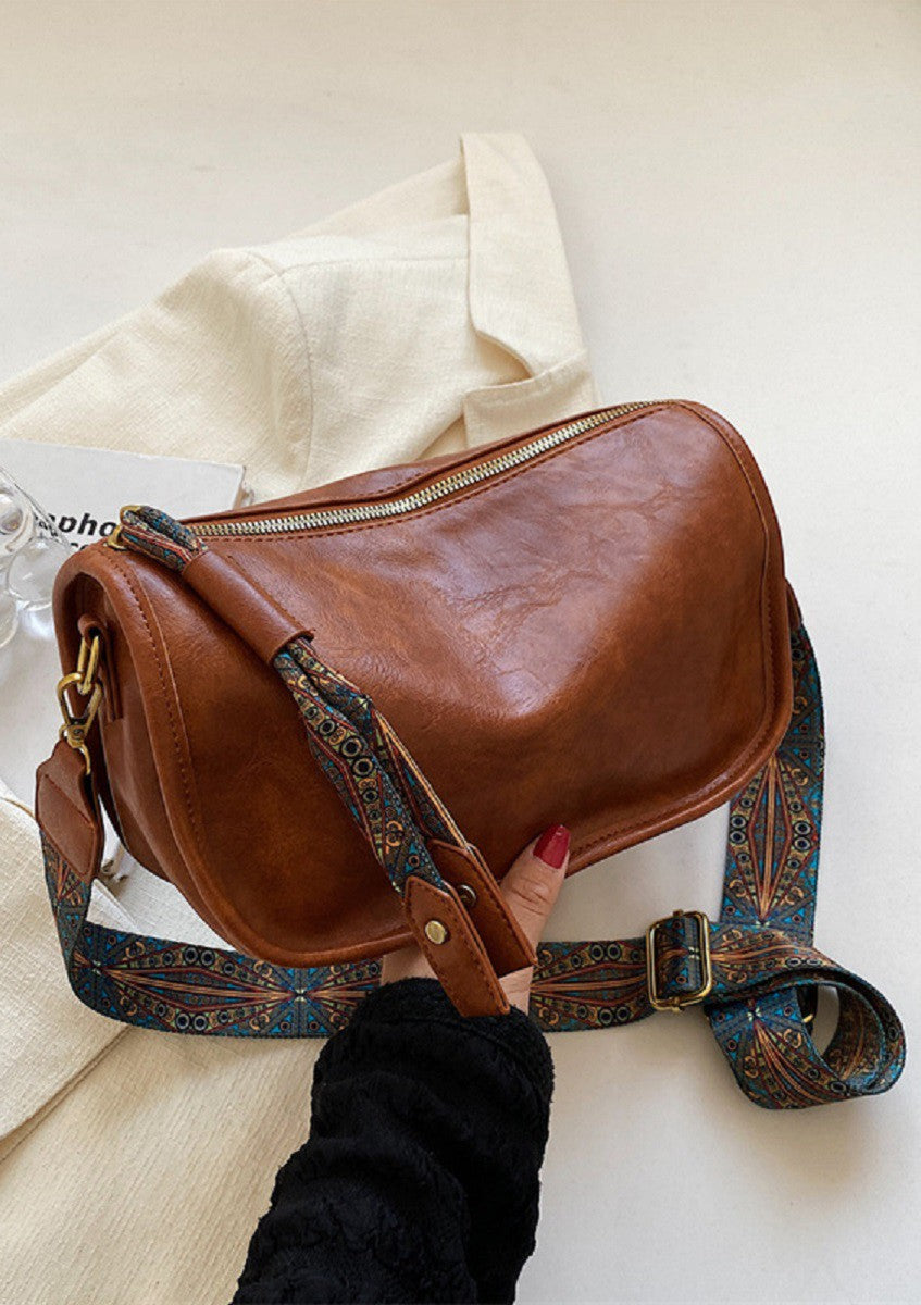 A person holding a Pattern Strap Zipper Shoulder Bag in Camel by FASHION GO.