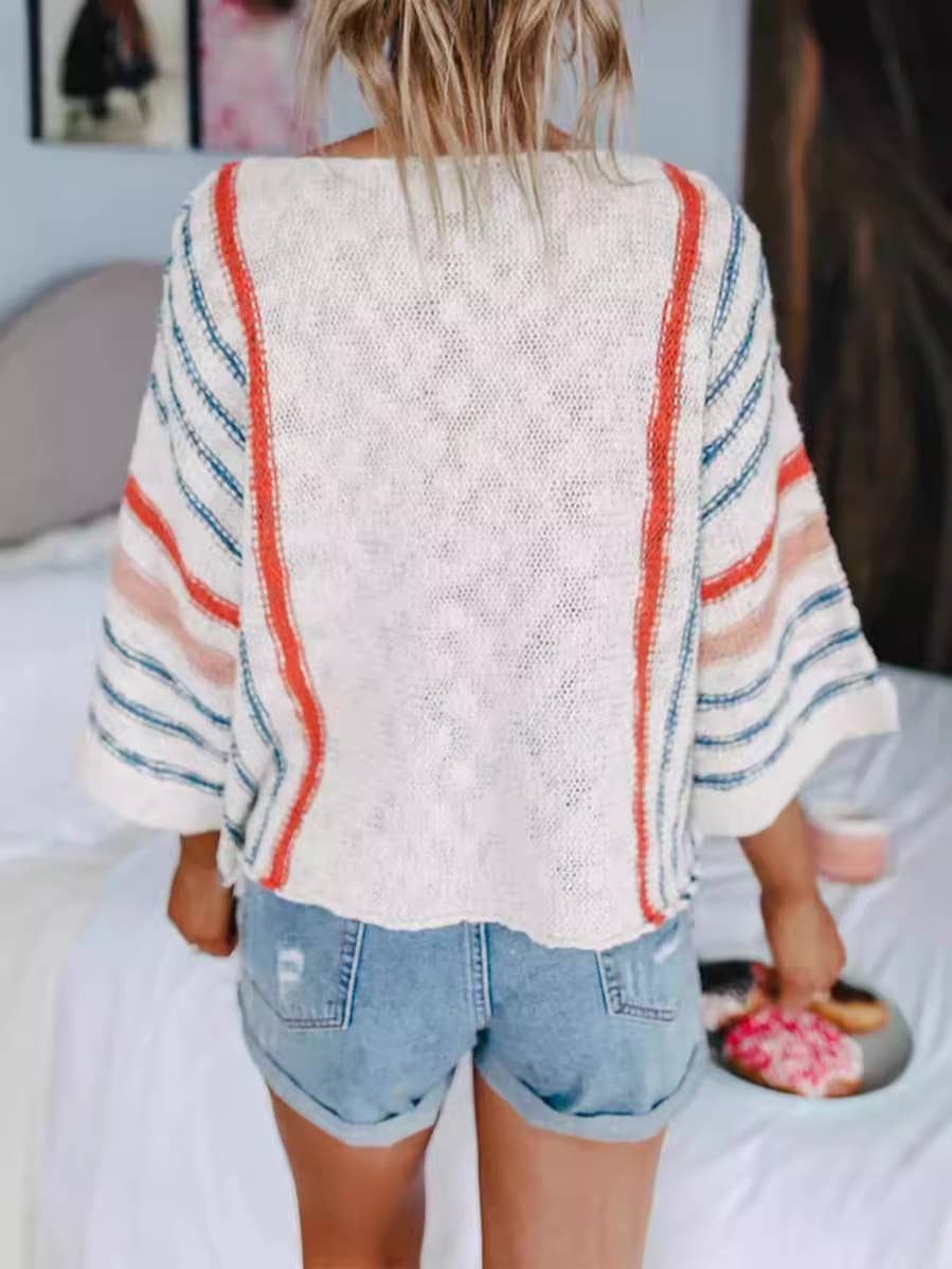 A person with blonde hair is seen indoors, facing away from the camera, wearing the Rosa Clothing Boho Flared Sleeve Loose Knit Sweater with stripes and denim shorts, while holding an object in their right hand.