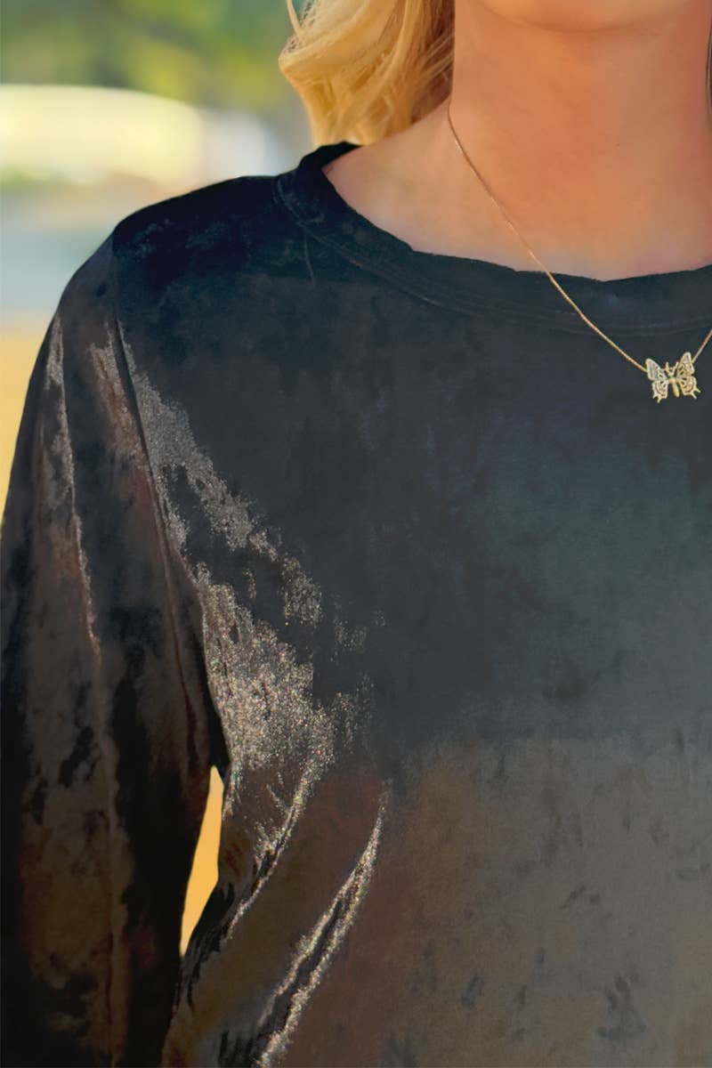 A close-up of a person outdoors wearing the 24-Hrs Fashion Crushed Velvet Top with flowy sleeves and a gold butterfly necklace, made in USA.