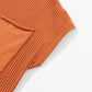 A close-up of Shewin's Patch Pocket Ribbed Knit Short Sleeve Sweater in rust, ideal for transitional weather, displayed on a light background.