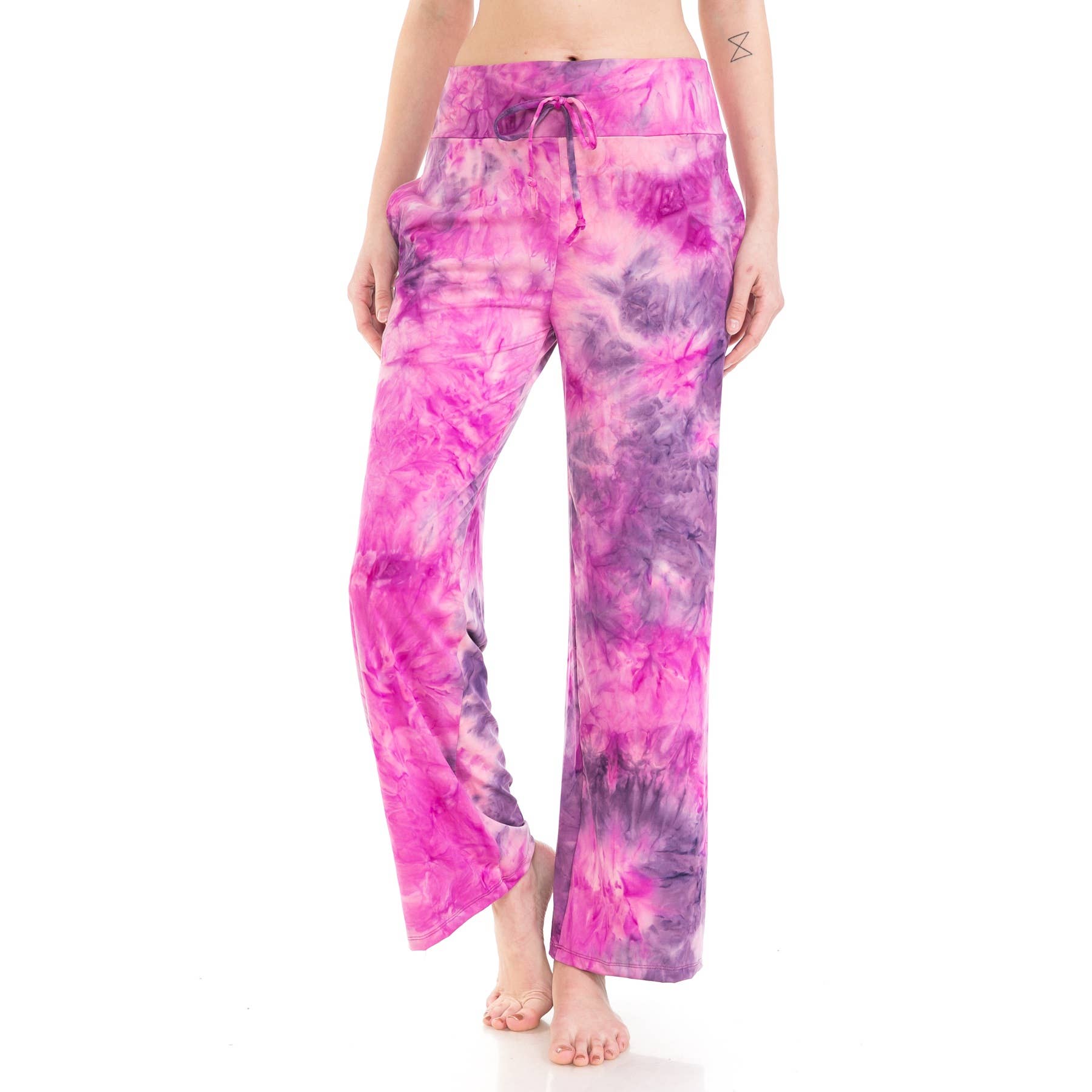 A person stands barefoot against a white background wearing Leggings Depot Buttery Soft Print Pajama Pants in pink and purple tie-dye with a drawstring waist.