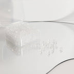 A clear plastic container from WJW holds one pair of their Silicone Earring Backs, with several secure, transparent earring backs scattered on a reflective surface nearby.