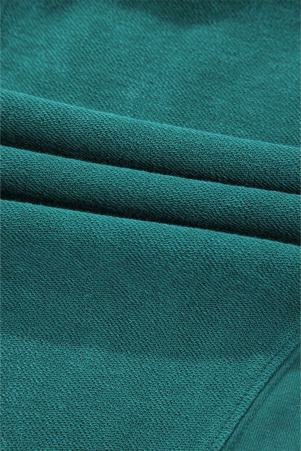 Close-up of soft, high-quality green fabric from Shewin's Notched Neck Exposed Seam Drop Shoulder Sweatshirt, perfect for comfort.