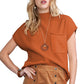 A woman poses with one hand on her hip, showcasing the Shewin Patch Pocket Ribbed Knit Short Sleeve Sweater in orange paired with a tan buttoned skirt, a necklace, and a bracelet—an ideal ensemble for transitional weather that blends warmth and style effortlessly.