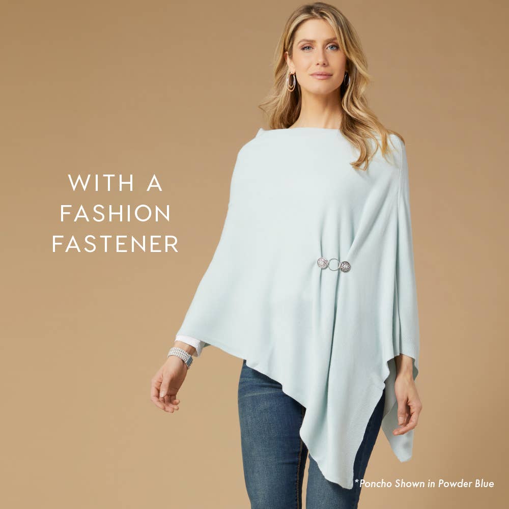 A woman wears a COCO + CARMEN Lightweight Ponchos Wrap in light blue with an asymmetrical hem, styled with a round silver fashion fastener. Text reads: “With a Fashion Fastener.”.