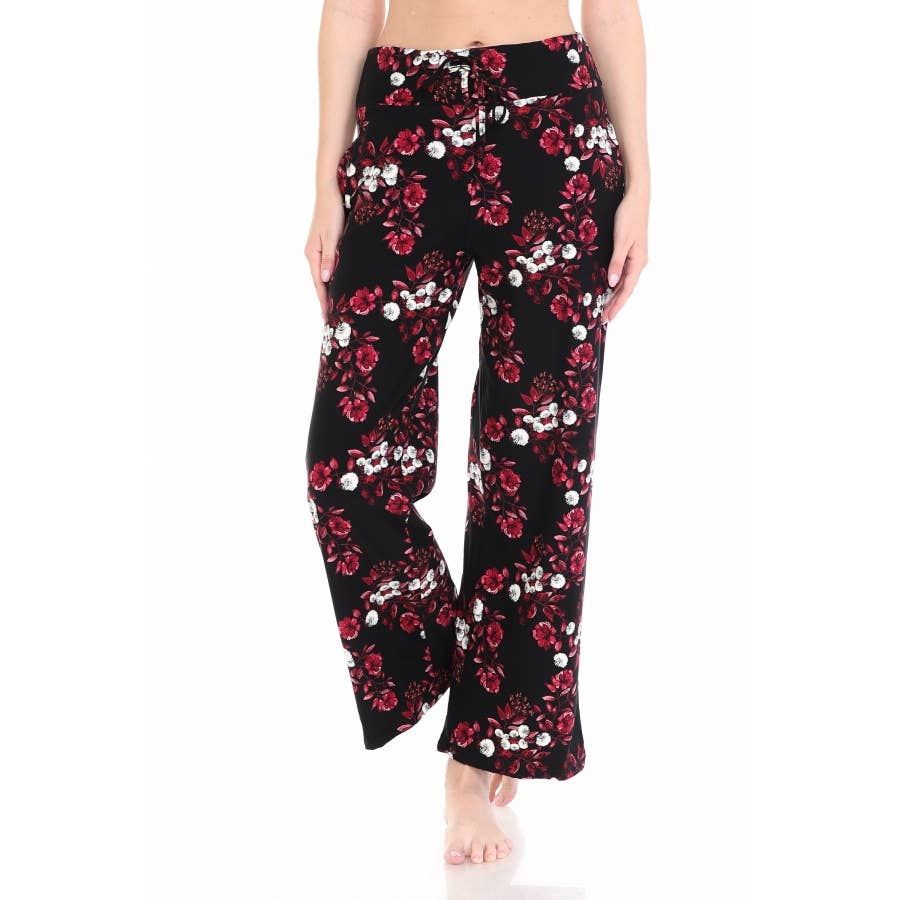 A person stands barefoot against a white background, wearing Leggings Depot Buttery Soft Print Pajama Pants in black with a red floral pattern and an elastic waistband.
