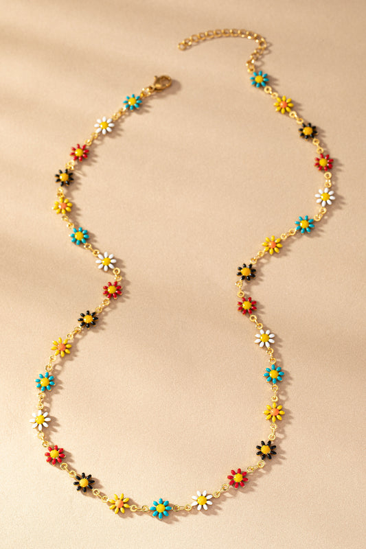 A colorful enamel Stainless Steel Daisy Necklace from FASHION GO with blue, yellow, red, and white flowers against a textured beige background.