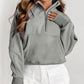 A woman with long, wavy hair wears a versatile Shewin Gray Zip Up Stand Collar Ribbed Thumbhole Sleeve Sweatshirt and white shorts, standing with her back partially turned.