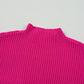 Close-up of a bright pink short sleeve sweater, crafted from cozy ribbed knit fabric by Shewin, against a light gray background.