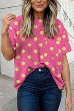 A person in the Aapparella Texture Polka Dot Chest Pocket T Shirt, a pink ribbed short-sleeve top, tucked into high-waisted dark jeans, stands on a sidewalk.