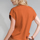 A blonde-haired individual wears a Shewin orange ribbed knit short sleeve sweater and a light brown skirt, seen from behind.